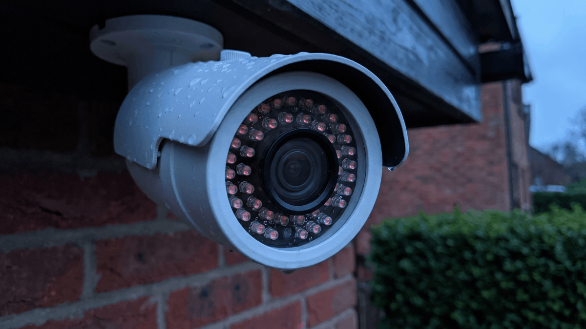 Infraroodleds rond de lens van een buitencamera gloeien zwak rood terwijl de avond valt.